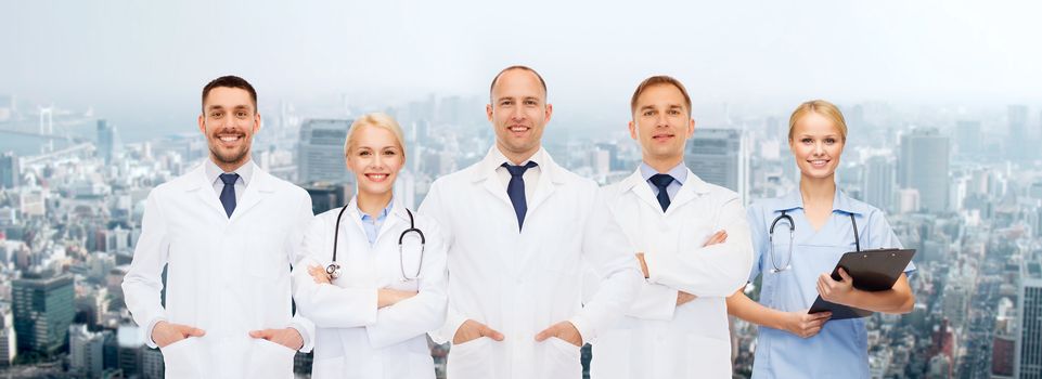 healthcare, people and medicine concept - group of doctors with stethoscopes and clipboard over city background