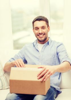 post, home and lifestyle concept - smiling man with cardboard boxes at home