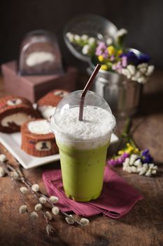 Iced green tea latte on wood table with low key scene