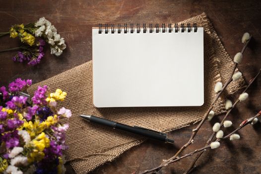 Small notepad with pen on rustic wood background with low key scene.