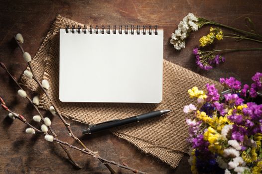 Small notepad with pen on rustic wood background with low key scene.