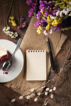 Small notepad with pen and pencil on rustic wood background with low key scene.