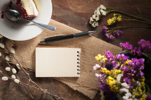 Small notepad with pen and pencil on rustic wood background with low key scene.