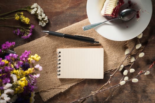 Small notepad with pen and pencil on rustic wood background with low key scene.