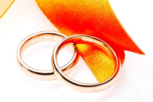 gold wedding rings near ribbon on white background
