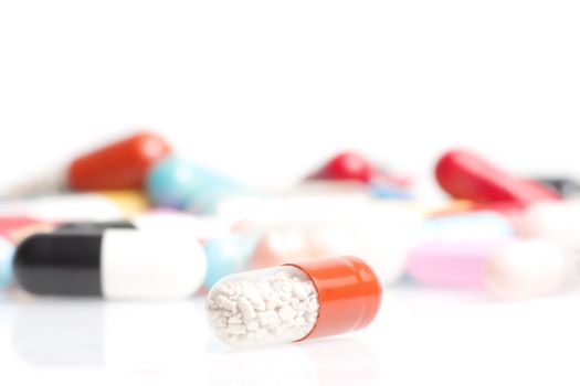 one medical pill in front of a lot of medical pills in laboratory on white table