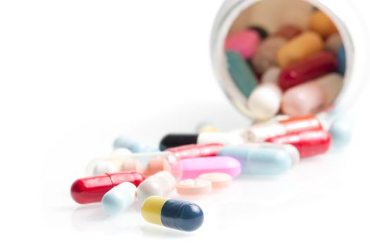 colored pills in laboratory near white container on white table with space for text