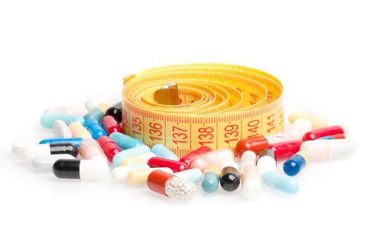 measuring tape with pills for dieting around on a white background