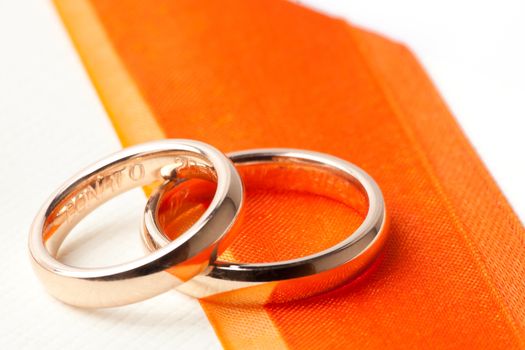 gold wedding rings near orange ribbon with space for text