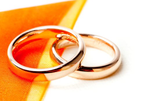 detail of gold wedding rings near orange ribbon