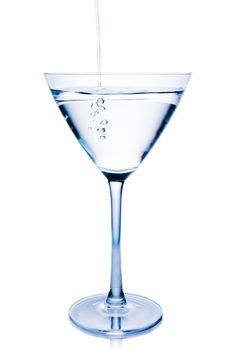 filling a  white cocktail in a glass with blue reflections on white background