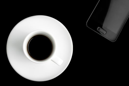 black smartphone and cup of coffee on black background