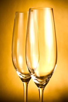 two empty glasses of champagne against golden background