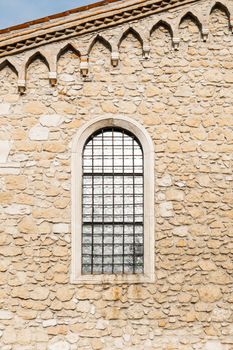 Arched window in the ancient medieval stone wall