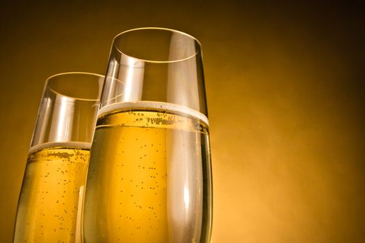 two glasses of champagne with golden bubbles against golden background