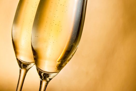 flutes of champagne with golden bubbles against golden background