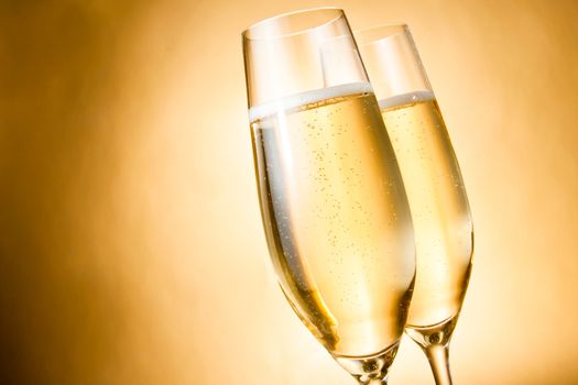 two glasses of champagne with golden bubbles against golden background