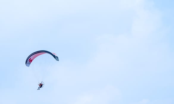 motorized paraglider flying in the blue sky