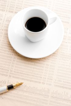 cup of coffee near a golden pen on financial newspaper 