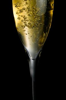 champagne flute with golden fine bubbles on black background