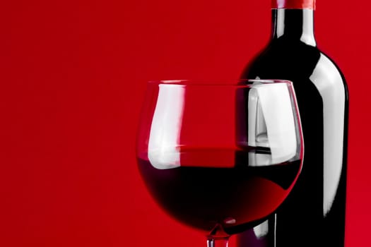 red wine glass and bottle on red background with space for the text