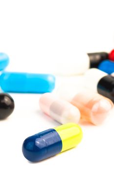 close up of one colorful pill in front of unfocused pills on white background