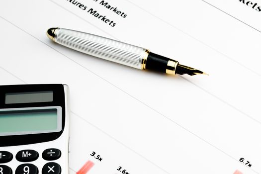 detail of calculator and pen on financial chart