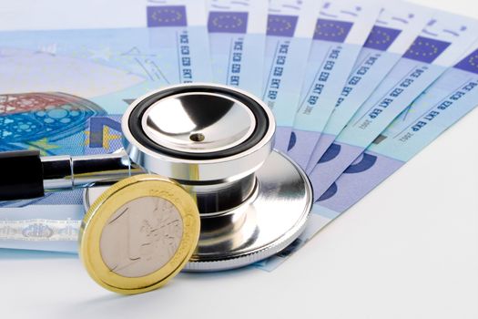 detail of stethoscope on banknote near euro coin on white background