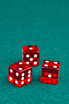 detail of three reds dice on green fabric background 