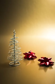 detail of silver christmas tree with red bows on gold background