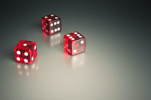 three red dice in the corner on a silver gaming table