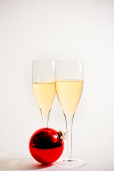 detail of glasses of champagne and christmas ball on white background