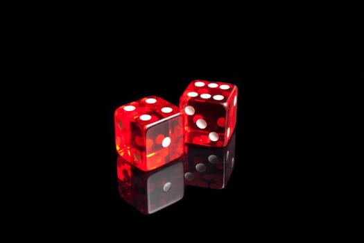 close up of a pair of dice on the black reflecting table