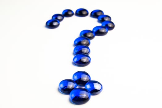 Detail view of  question mark drawn with blue stones on white background