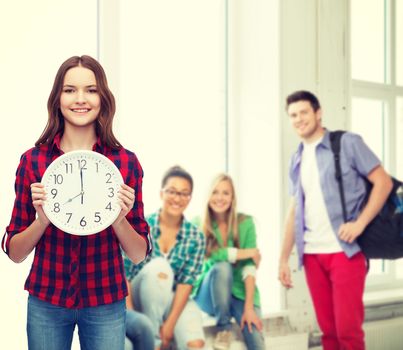 happiness and people concept - smiling young woman in casual clothes with wall clock showing 8 oclock