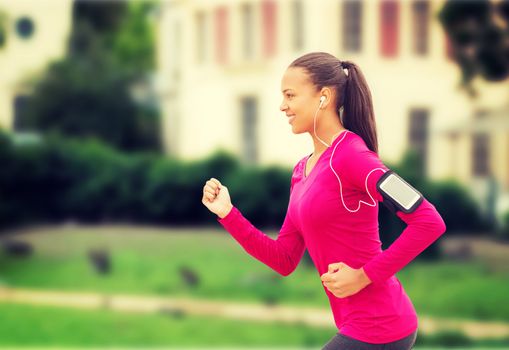 sport, fitness, health, technology and people concept - smiling young african american woman running with smartphone and earphones outdoors