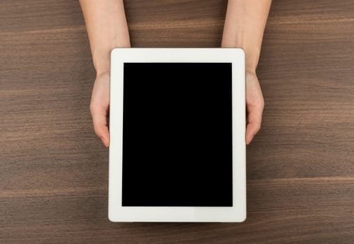 Humans hands holding tablet on wooden table background