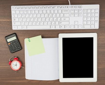 Tablet with office supplies on wooden table