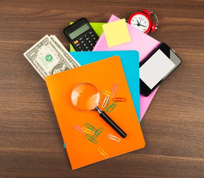 Colorful notebooks with magnifier on wooden table