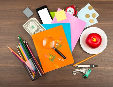 Colorful notebooks with office supplies and apple on wooden table