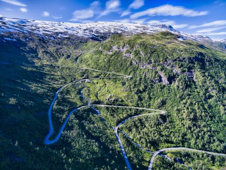 Aerial view of serpentine mountain road in Gaularfjellet mountain pass in Norway surrounded by snowy mountain peaks
