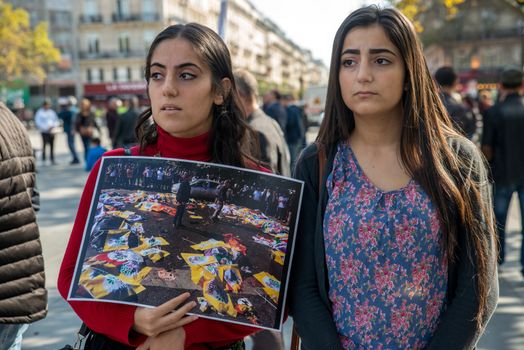 FRANCE, Paris: Two women stand holding a picture of Ankara terror attack while protesters gather in Place de la R�publique in Paris on October 10, 2015, in tribute to the victims of the terror attack. The same day, at least 95 people died after a twin explosion in the center of the capital city in Turkey. 