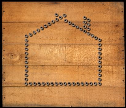 Many screws in the shape of house on a brown wooden background with nails. isolated on black background.