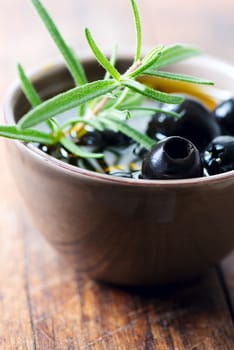 Black olives in clay bowl and rosemary set