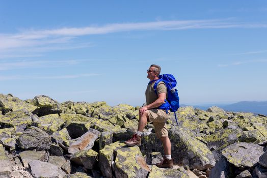 Hiker with big traveling rucksack looking forward on the mountain trail, adventure travel and discovery