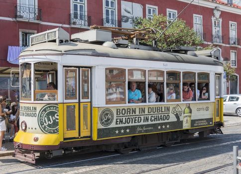 LISBON, PORTUGAL - SEPTEMBER 26: Unidentified people sitting in the Yellow tram  goes by the street of Lisbon city center on September 26, 2015. Lisbon is a capital and must famous city of Portugal