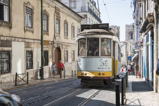 LISBON, PORTUGAL - SEPTEMBER 26: Unidentified people sitting in the Yellow tram  goes by the street of Lisbon city center on September 26, 2015. Lisbon is a capital and must famous city of Portugal