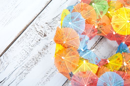 Little party umbrellas in circle on light blue wooden background