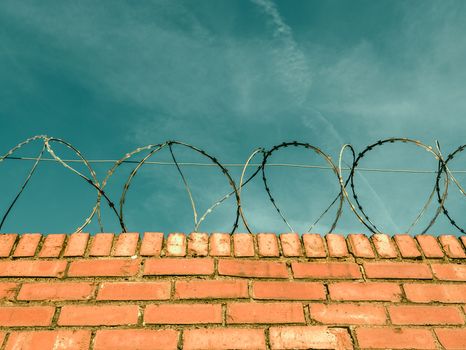 Barbed Or Razor Wire On Top Of A Red Brick Wall Around Private Property