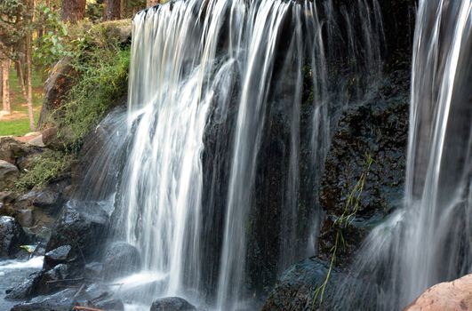 Poland.Park in Warsaw.Autumn.October.Small waterfall in the park.Water falling from the top of the stones.Horizontal view.